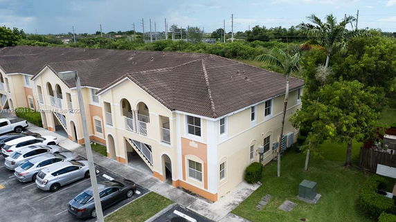 Front view of a two-story apartment building with arches and a parking area.