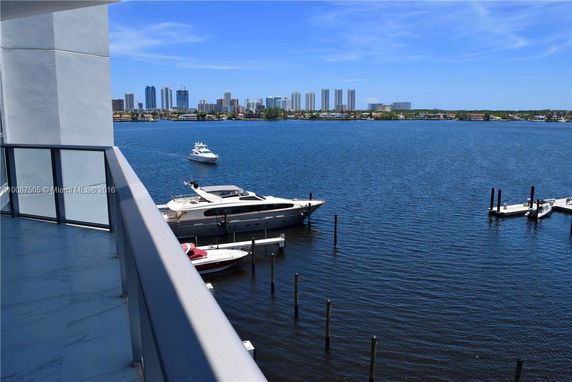 Balcony view of a waterfront with boats and a city skyline in the distance.