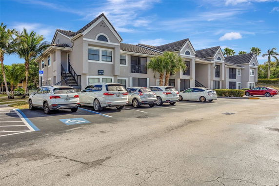 Parking area in front of a two-story residential building with multiple cars.