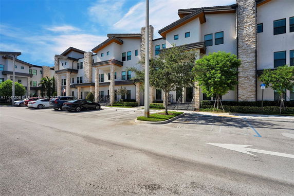 Front view of a multi-story building with stone accents and several parked cars.