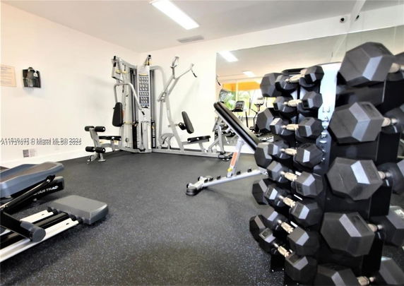 Indoor gym with fitness equipment including weights and machines.