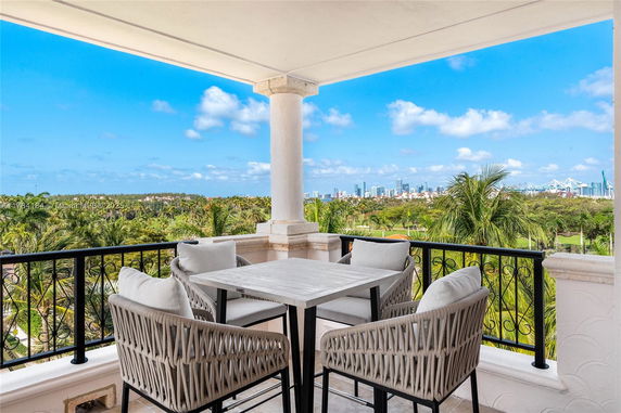 Balcony with a table and chairs overlooking a landscape with city skyline in the distance.