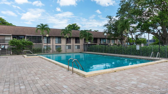 Outdoor swimming pool with a two-story residential building in the background.