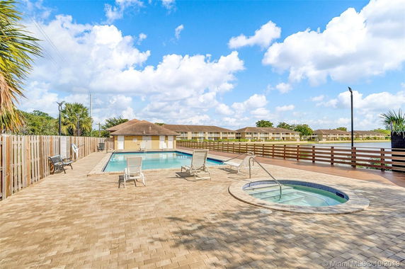 Outdoor swimming pool area with lounge chairs and a hot tub.
