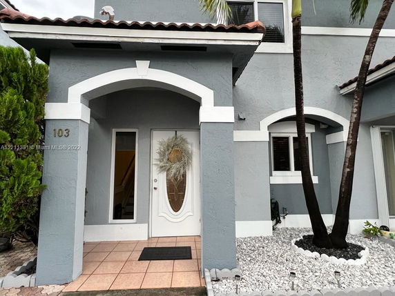 Front view of a two-story house with an arched entranceway and decorative white trim.