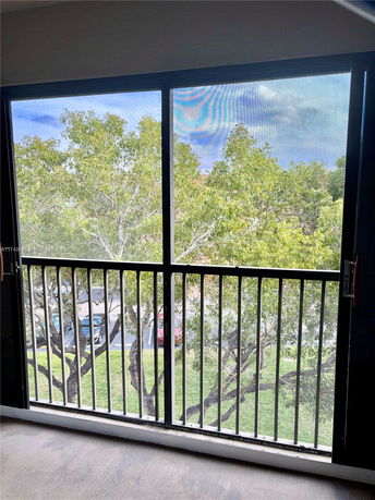 View from a balcony showing trees and parked cars below.
