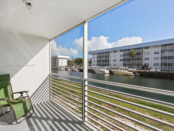 View from a screened balcony overlooking water and adjacent apartment buildings.
