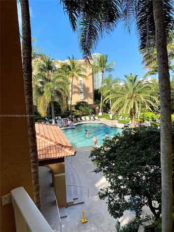 Outdoor view with a swimming pool surrounded by palm trees and lounge chairs.