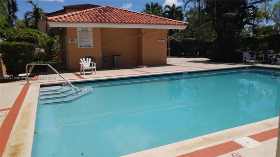Outdoor swimming pool with surrounding seating and changing rooms.