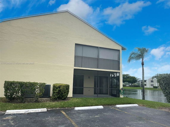 Front view of a two-story building with screened balcony and parking area.