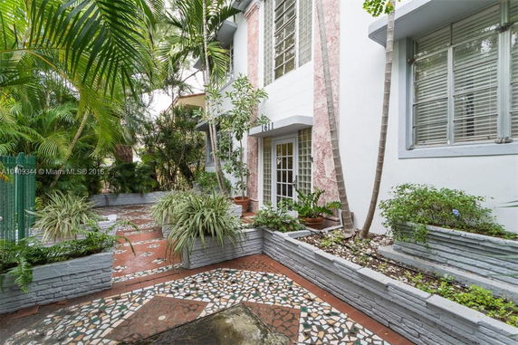 Front view of a house with decorative plants and patterned tile pathway.