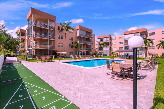 Outdoor swimming pool area surrounded by multi-story residential buildings.