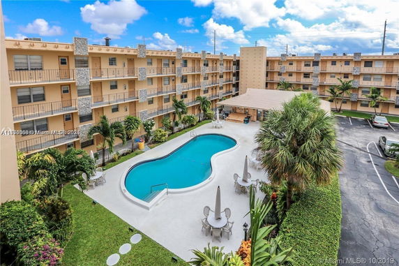 Outdoor area with a rectangular swimming pool surrounded by a multi-story residential building.