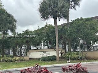 Front view of a residential building with trees and a sign.