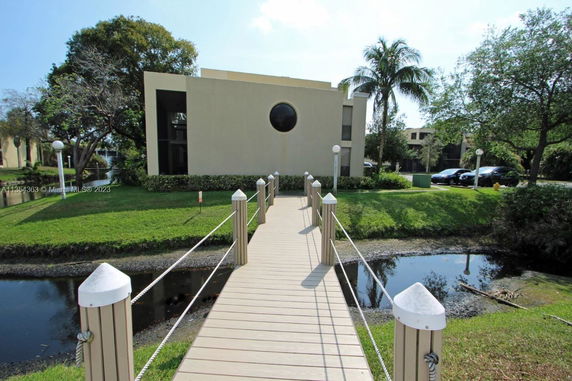 Front view of a modern two-story building with a circular window and a wooden walkway leading to it.