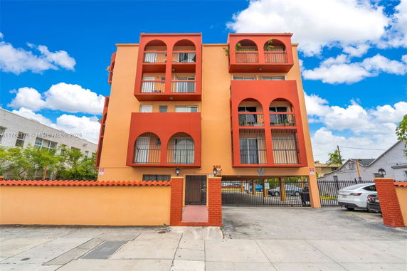 Front view of a multi-story orange apartment building with arched balconies.