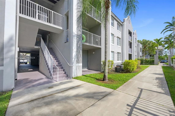 Front view of a multi-story apartment building with balconies and a staircase.
