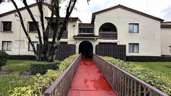Front view of a two-story residential building with a walkway and archway entrance.