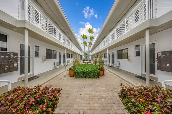 View of a two-story building corridor with plants and potted shrubs.
