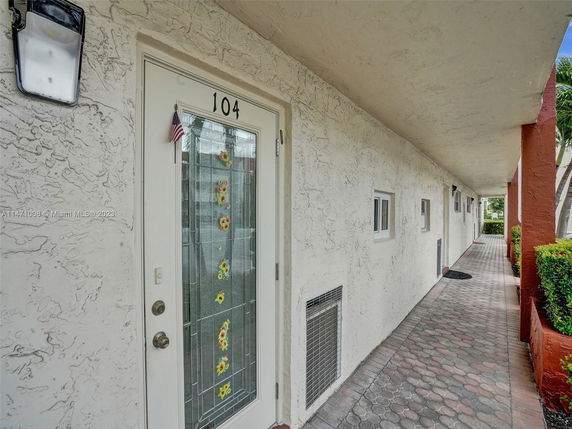 Front view of a building entrance with a decorative glass door and walkway.
