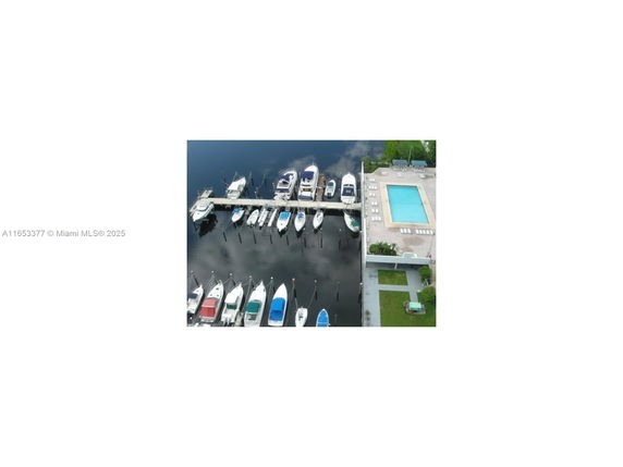 Aerial view of a swimming pool next to a marina with multiple boats docked.