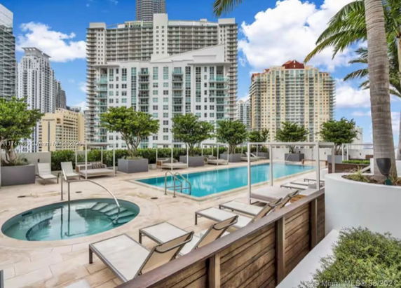Outdoor swimming pool area on rooftop with city buildings in the background.