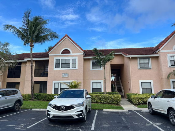 Front view of a two-story building with a central staircase and parking area in front.