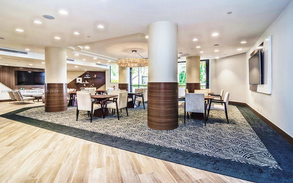 Interior view of a recreational area with tables, chairs, and a TV.