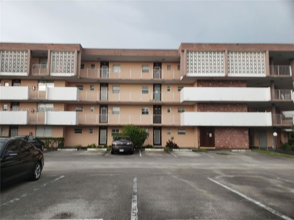 Front view of a multi-story building with balconies and parking area.