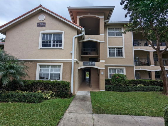 Front view of a multi-story residential building with balconies and a central walkway.