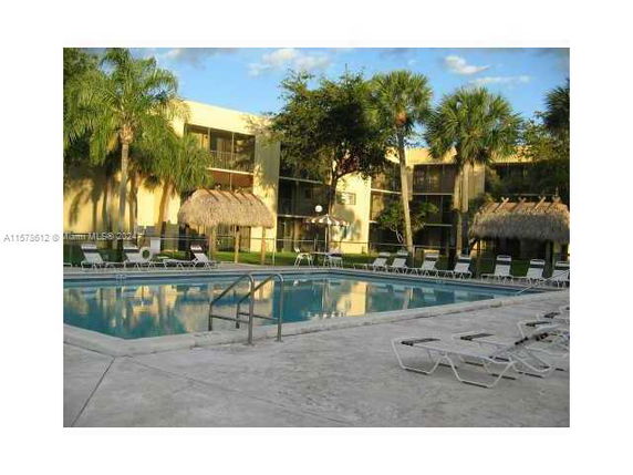 Outdoor swimming pool area with lounge chairs and surrounding trees.
