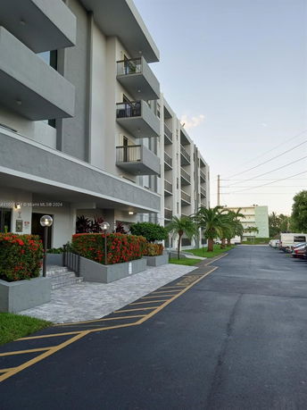 Front view of a multi-story residential building with balconies and landscaped entrance.