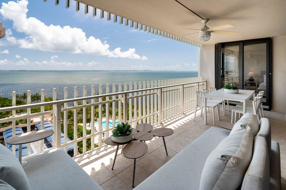 Terrace view overlooking a body of water with outdoor seating and dining area.