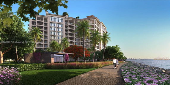 View of a multi-story residential building near a waterfront with a walking path and landscaping.
