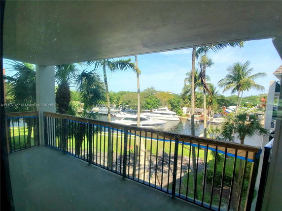 Balcony view overlooking a waterfront area with boats and palm trees.