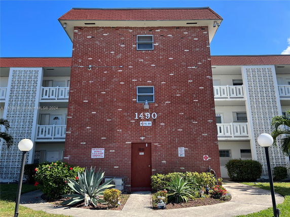 Front view of a three-story brick apartment building with balconies.