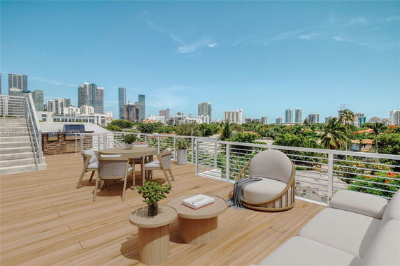 Rooftop view with a wooden deck, outdoor furniture, and city skyline in the background.