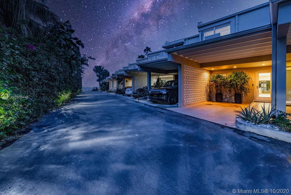 Outdoor parking area with multiple carports at night, under a starry sky