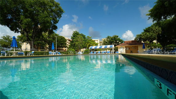 Outdoor swimming pool area with surrounding trees and lounging chairs.