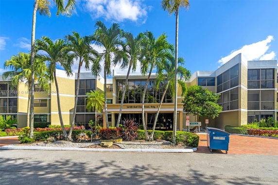 Front view of a multi-story building with large windows and palm trees.