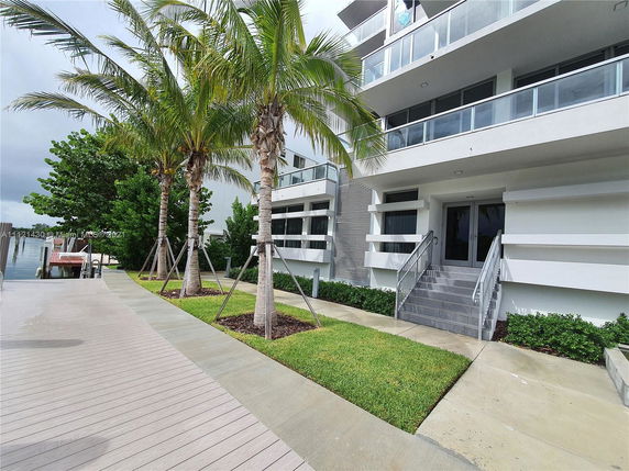Front view of a multi-story building with balconies and palm trees.