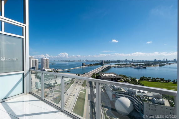 View from a high-rise building balcony overlooking a bridge and body of water with city skyline in the distance.