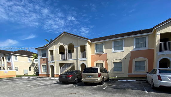 Front view of a two-story residential building with balconies and parking spaces.