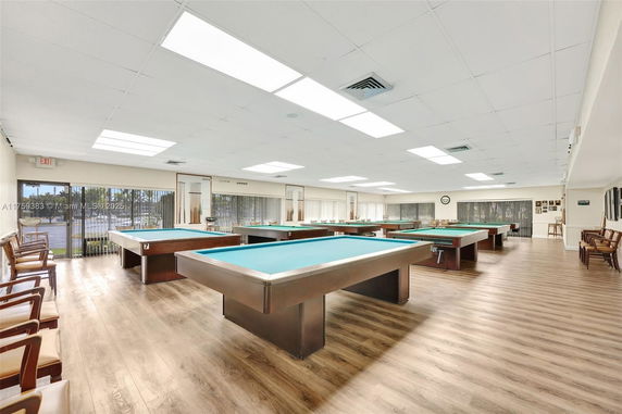 Room with multiple billiard tables and seating areas.