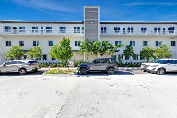 Front view of a three-story building with balconies and a central entrance.