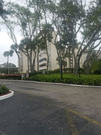 Front view of a multi-story apartment building with trees in the foreground.