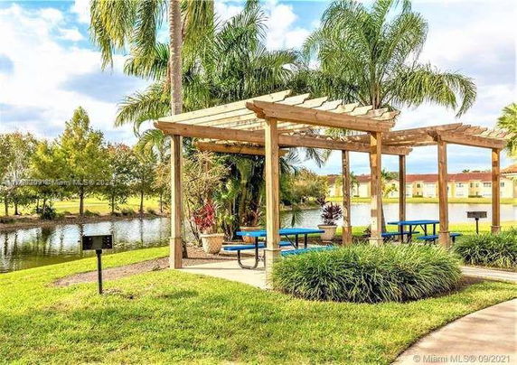 Outdoor seating area with pergola near a body of water.
