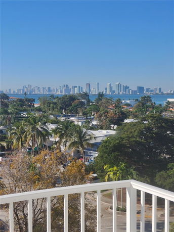 Panoramic view from a balcony overlooking a city skyline and water.