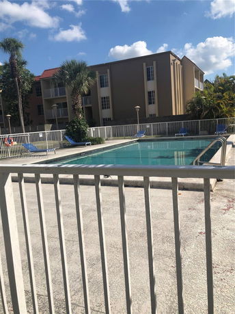 Outdoor swimming pool area with a building in the background.