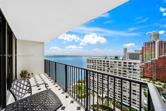 Panoramic view from a balcony overlooking the ocean and surrounding city buildings.